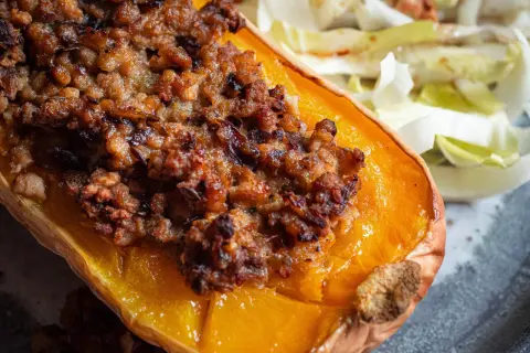 Moitié de courge butternut farcie, une recette savoureuse avec une garniture dorée et croustillante, servie avec une salade fraîche.