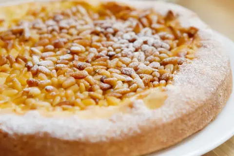 Deliciosa tarta de piñones, cubierta con azúcar glas, lista para disfrutar.