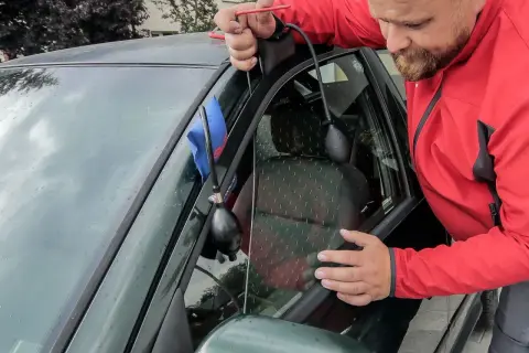 Mężczyzna używa narzędzia do otwierania drzwi, gdy zatrzaśnięte kluczyki w samochodzie jak otworzyć.