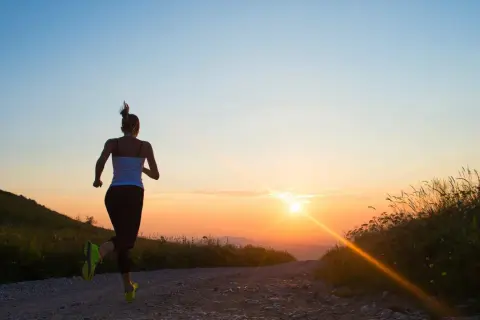 Läuferin genießt den Sonnenaufgang. Die beste Zeit zum Trainieren ist oft früh am Morgen, wenn die Natur erwacht.