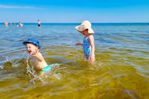 Dzieci bawią się w wodzie na plaży, jednej z urokliwych miejscowości blisko Gdańska.