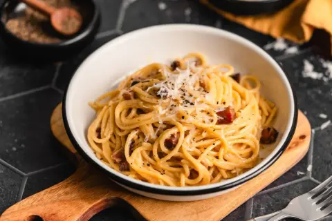 Ein Teller Spaghetti Carbonara, garniert mit Parmesan und schwarzem Pfeffer. Perfekt für Ihre Carbonara Rezepte.
