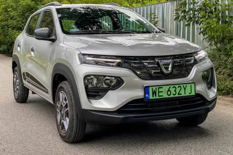 Srebrna Dacia Spring z zieloną tablicą rejestracyjną. Ten elektryczny samochód oferuje imponujący zasięg, idealny na miejskie podróże.