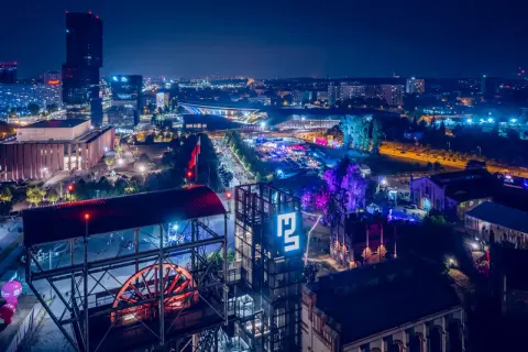 Nocny festiwal Tauron Nowa Muzyka w Katowicach. Widać sceny, tłumy ludzi i charakterystyczne budynki postindustrialne.