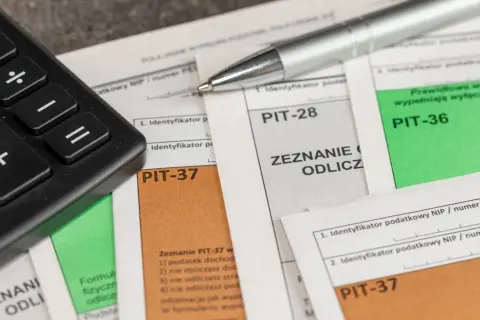 Kalkulator i długopis na dokumentach PIT. Przygotowanie do rozliczenia ulgi rehabilitacyjnej na samochód.