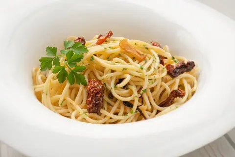 Espaguetis al ajillo, un plato sencillo pero delicioso, con pasta dorada, trozos de ajo crujiente y perejil fresco.
