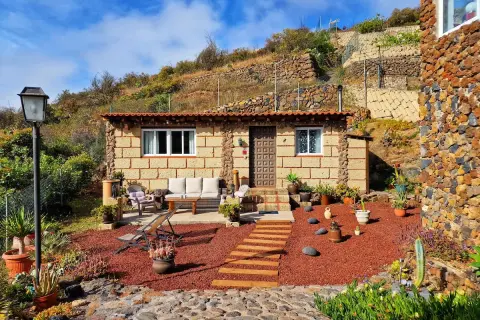 Acogedora casa rural de piedra, rodeada de plantas y con un camino de madera que lleva a la entrada. Un lugar perfecto para disfrutar de la tranquilidad de el escobonal.