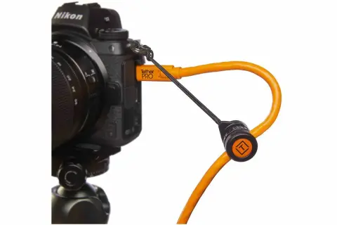 En orange Tether Tools-kabel ansluten till en Nikon-kamera, redo för säker överföring av bilder.