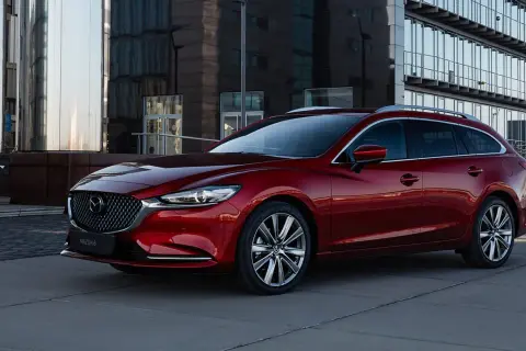 Czerwone kombi Mazda 6 na tle nowoczesnego budynku. Poznaj jej wymiary i możliwości.