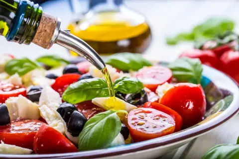 Sałatka caprese z pomidorów, mozzarelli, oliwek i bazylii, polana oliwą z oliwek. Idealna na zdrową dieta śródziemnomorska.
