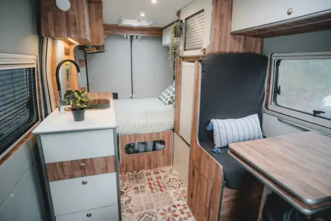 Interior de camper con cama, cocina y zona de asientos. ¡Ideas camper para tu próxima aventura!