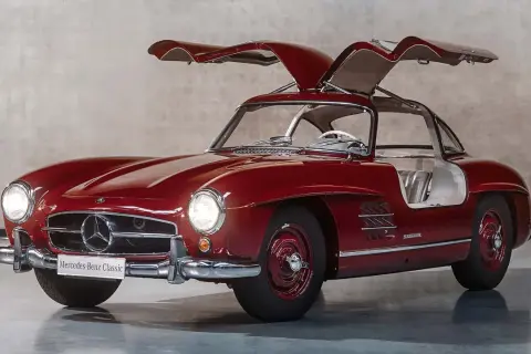 Czerwony Mercedes 300 SL z otwieranymi do góry drzwiami, prezentujący swoje klasyczne piękno.
