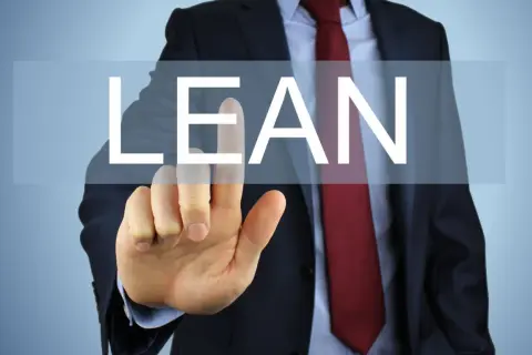 Biznesmen w garniturze dotyka ekranu z napisem "LEAN".
