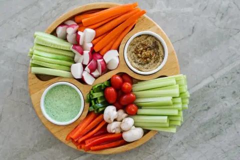 Bunter Gemüseteller mit Hummus und Dip – perfekt für einen 1000 kcal am Tag Essensplan. Karotten, Gurken, Radieschen, Paprika, Tomaten, Sellerie und Pilze.