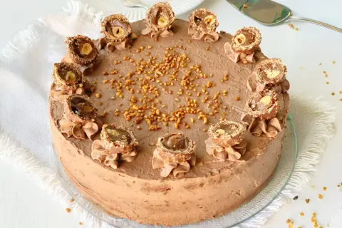 Eine köstliche Rocher Torte mit Schokoladencreme und gehackten Nüssen, dekoriert mit halbierten Rocher Kugeln.