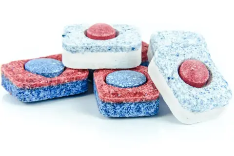 Kilka kostek do zmywarki w kolorach czerwonym, niebieskim i białym. Co zamiast tabletki do zmywarki? Te kostki to rozwiązanie!