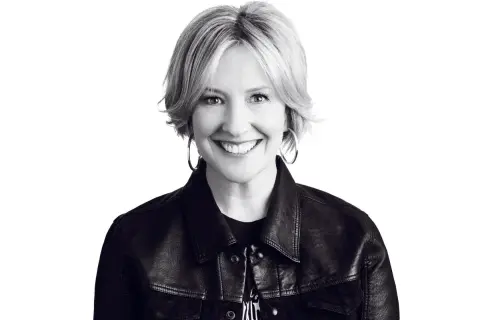 Uśmiechnięta Brené Brown w skórzanej kurtce, uosobienie odwagi i autentyczności.