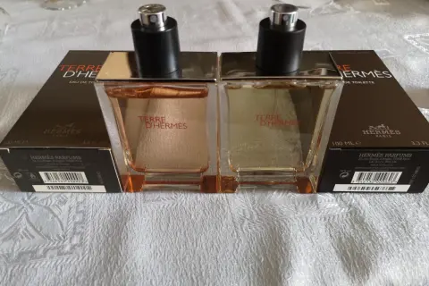 Dwa flakony Terre d'Hermès EDT, każdy 100 ml, stoją na białym obrusie.