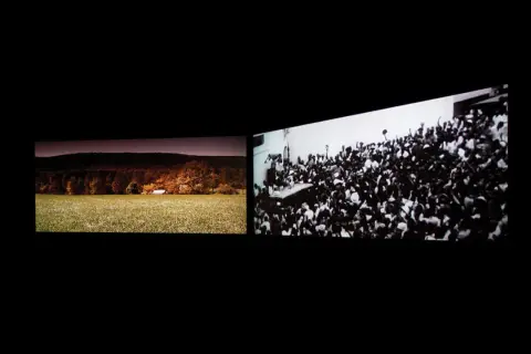 John Akomfrah art: a split screen showing a pastoral landscape with a small building and a dense crowd of people cheering.