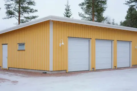 Gult garage med tre vita garageportar, redo att måla om.