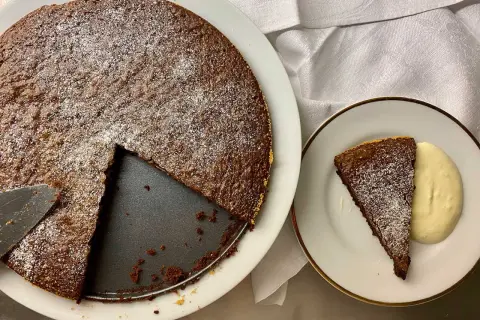 Chokladkaka med pudersocker, en bit serverad med grädde. Perfekt för att baka snabbt och enkelt.