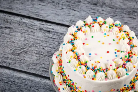 Torta bianca decorata con panna e confettini colorati, un esempio di torte di compleanno particolari per una festa allegra.