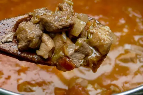 Gulasz wieprzowy na drewnianej łyżce. Kiedy solić mięso wieprzowe na gulasz? Najlepiej na początku, by wydobyć smak.