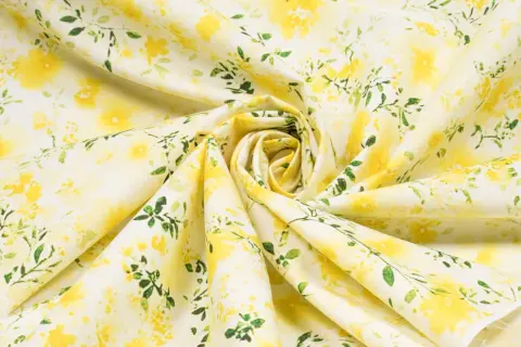 Ein zartes Popeline-Gewebe mit einem gelben Blumenmuster und grünen Blättern, das an einen sonnigen Frühlingsgarten erinnert.