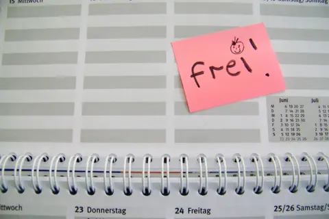 Ein rosa Zettel mit "frei!" und einem lachenden Smiley auf einem Kalenderblatt. Der Zettel könnte für den Freizeitausgleich nach Krankheit stehen.