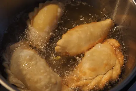 Empanadas de queso dorándose en aceite burbujeante. El aroma tentador llena la cocina.