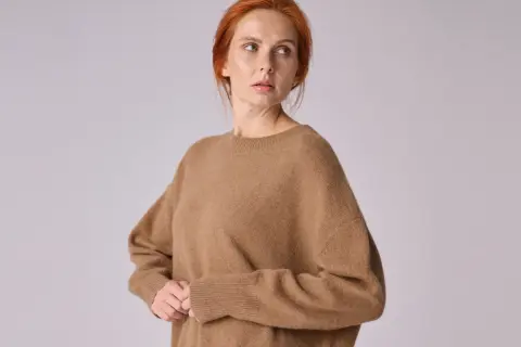 Kobieta w brązowym swetrze z wełny wielbłądziej.