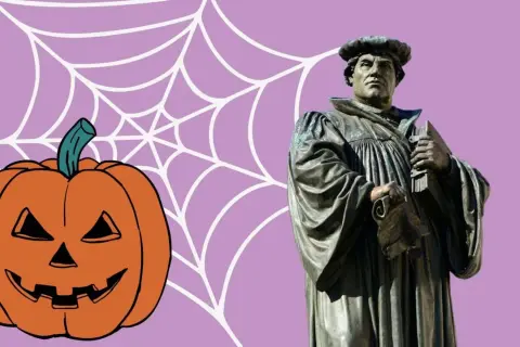 Reformationstag statt Halloween: Martin Luther Statue neben Kürbis und Spinnennetz.