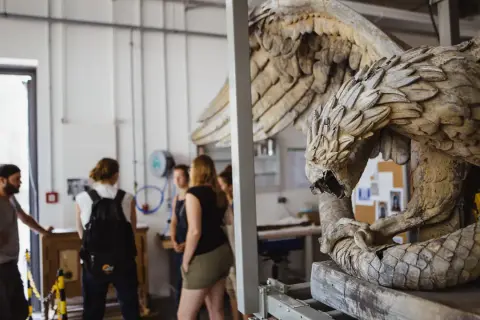 Studierende im Restaurationsstudium betrachten eine detailreiche Skulptur eines geflügelten Wesens.