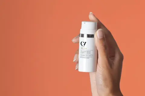 Hand hält Flasche mit "Collagen Boost Vitamin C Serum". Perfekt für Ihre Vitamin C Skincare Routine.