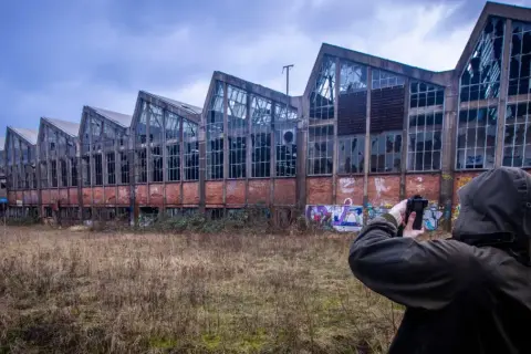 Exploration urbex à Angoulême : une silhouette capture l'architecture délabrée d'une usine abandonnée, ornée de graffitis.