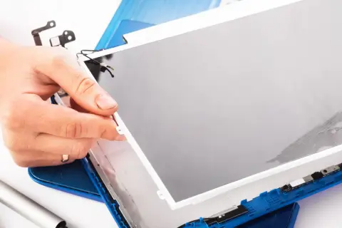 Dłoń trzyma nową matrycę do laptopa, gotową do montażu. Wymiana matrycy w laptopie to precyzyjna praca.