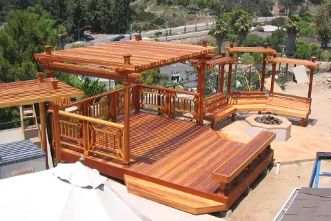 Terraza de madera de secuoya con pérgolas, bancos y hoguera. Un espacio ideal para disfrutar al aire libre.