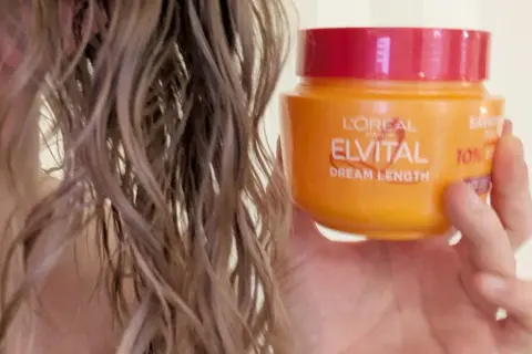 En hand håller en burk L'Oréal Elvital Dream Length hårinpackning bredvid vått hår. Hur ofta hårinpackning behövs beror på hårets skick.