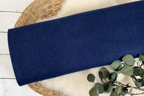 Dunkelblauer Denim-Stoff, aus dem Jeans gemacht sind, liegt auf einem Schaffell.
