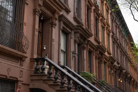 Brązowe kamienice w stylu brownstone, typowe dla Harlem, Nowy Jork, z ozdobnymi detalami i schodami.