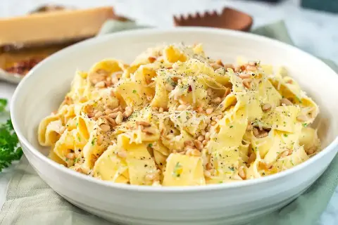 En skål med krämig citronpasta, toppad med pinjenötter och riven parmesan. En härlig rätt som passar perfekt för en snabb middag.