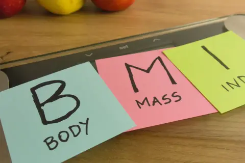 Na wadze leżą karteczki z napisem "BODY MASS INDEX". Dążenie do prawidłowego BMI to klucz do zdrowia.