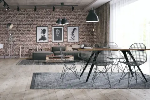 Surowy, betonowy sufit w stylu loft nadaje wnętrzu industrialnego charakteru. Ceglana ściana, grafiki i metalowe meble dopełniają ten surowy klimat.