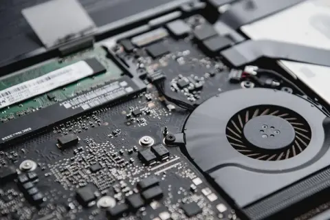 Detalle de la placa base de un portátil, mostrando un módulo de memoria RAM y el ventilador de refrigeración.