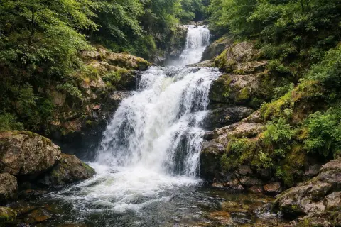 La cascade des Jarrauds dévale une pente rocheuse verdoyante, ses eaux vives se jetant dans un bassin limpide.