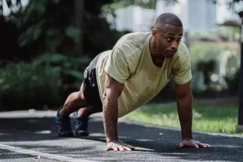 A determined boxer performs push-ups outdoors. This exercise builds the upper body strength crucial for delivering powerful punches and absorbing blows.
