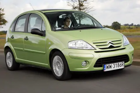 Zielony Citroen C3 z 2003 roku jedzie po drodze, za kierownicą młody mężczyzna.