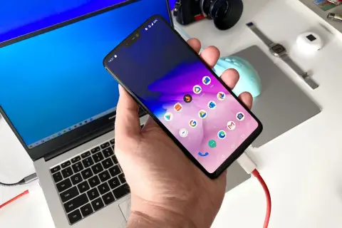 Podłączony do laptopa smartfon, gotowy do transferu danych. Prosty sposób, jak zgrać zdjęcia z telefonu na komputer.