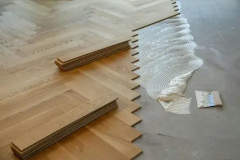 Układanie parkietu jodełkowego na legarach. Klej czeka na deseczki, by stworzyć piękną podłogę.