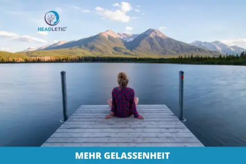 Eine Frau sitzt auf einem Steg am See, blickt auf Berge. Ähnlich gelassen wie Kardinal Ratzinger in stiller Kontemplation.